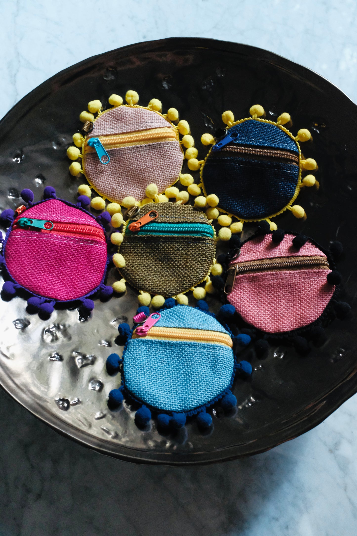 Back view of handmade colorful coin pouches with pom pom trim and zippers