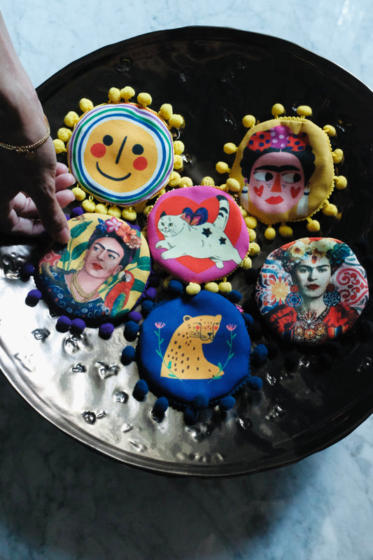Front view of artistic handmade coin pouches with fun prints and pom pom edges